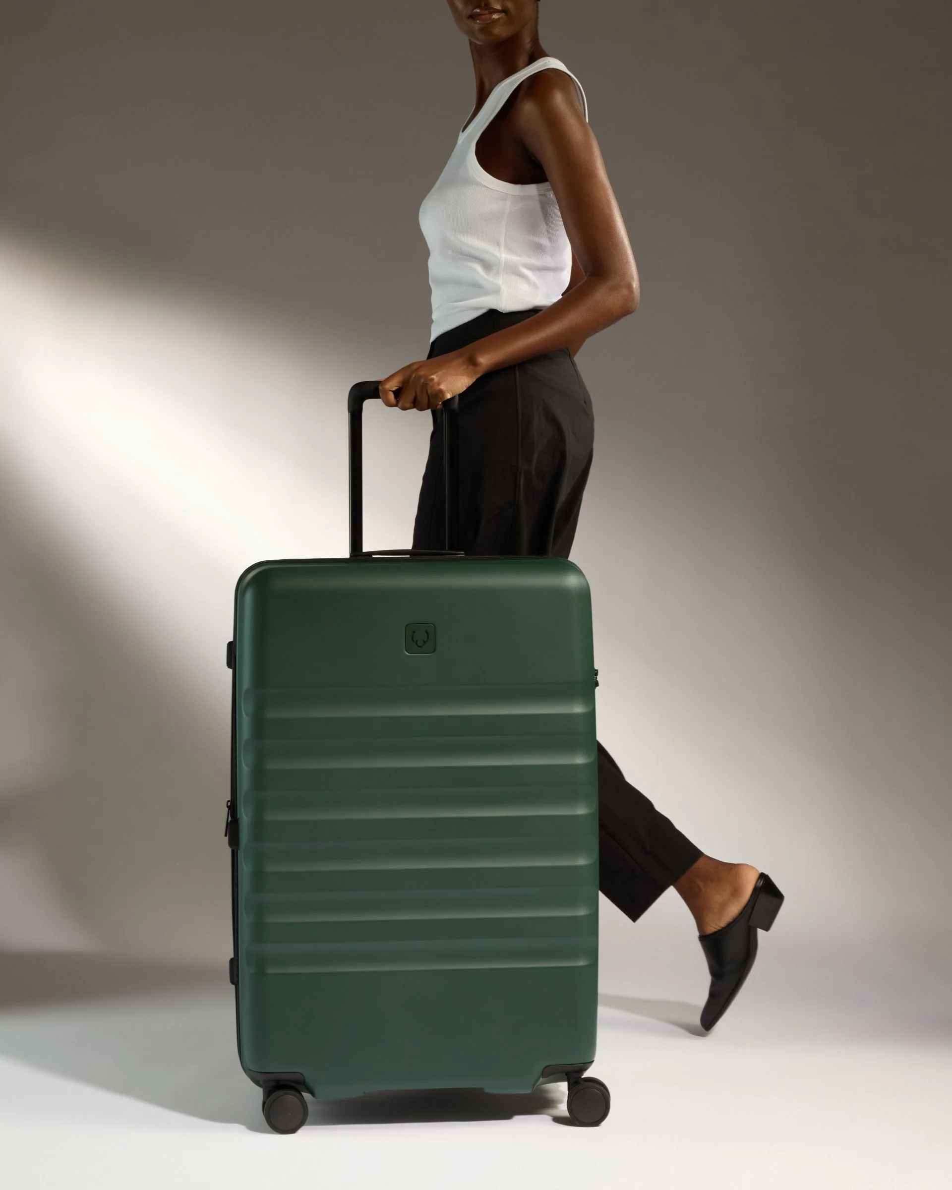 Model walking with green Antler luggage.
