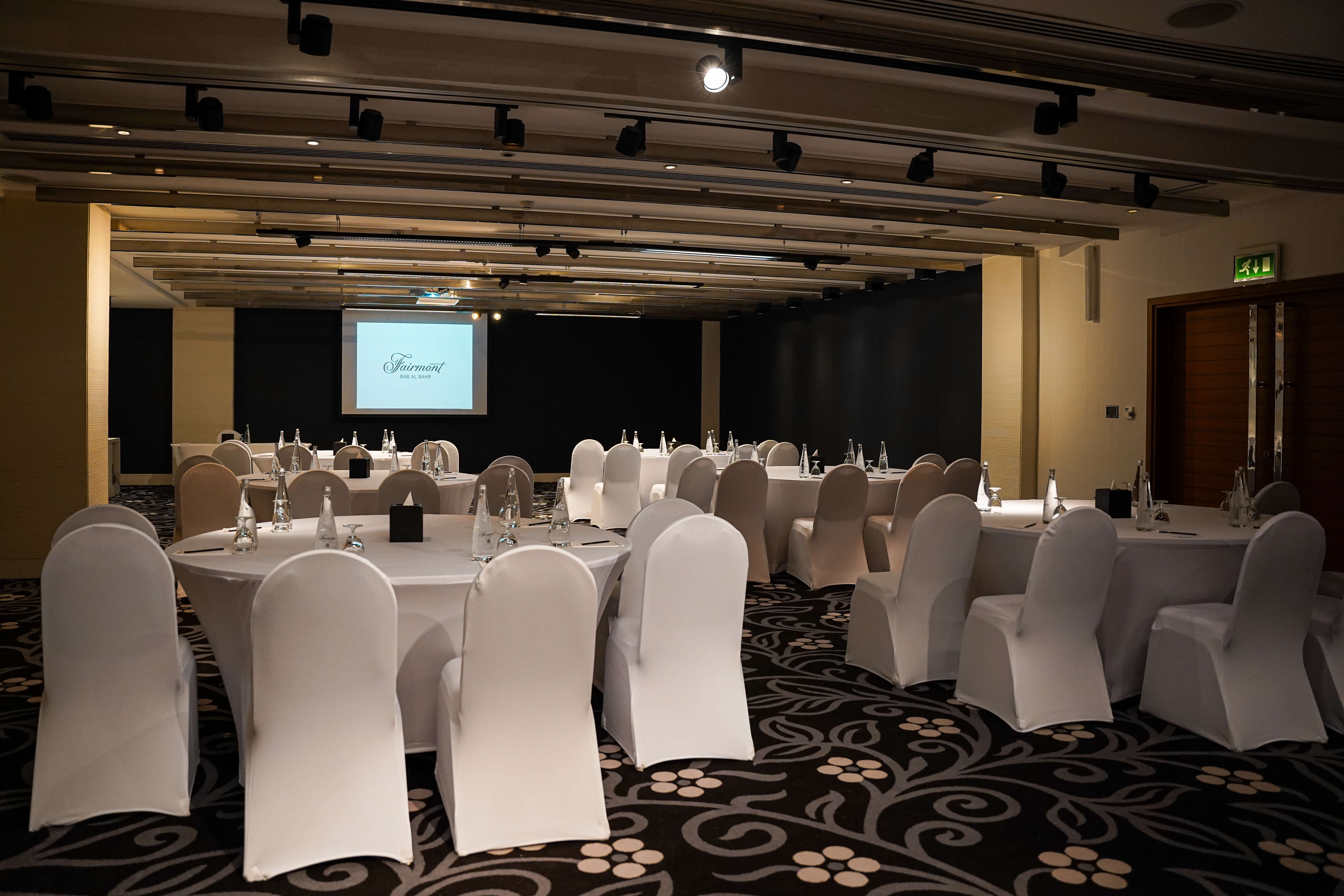 Fairmont meeting room with round tables and presentation screen.