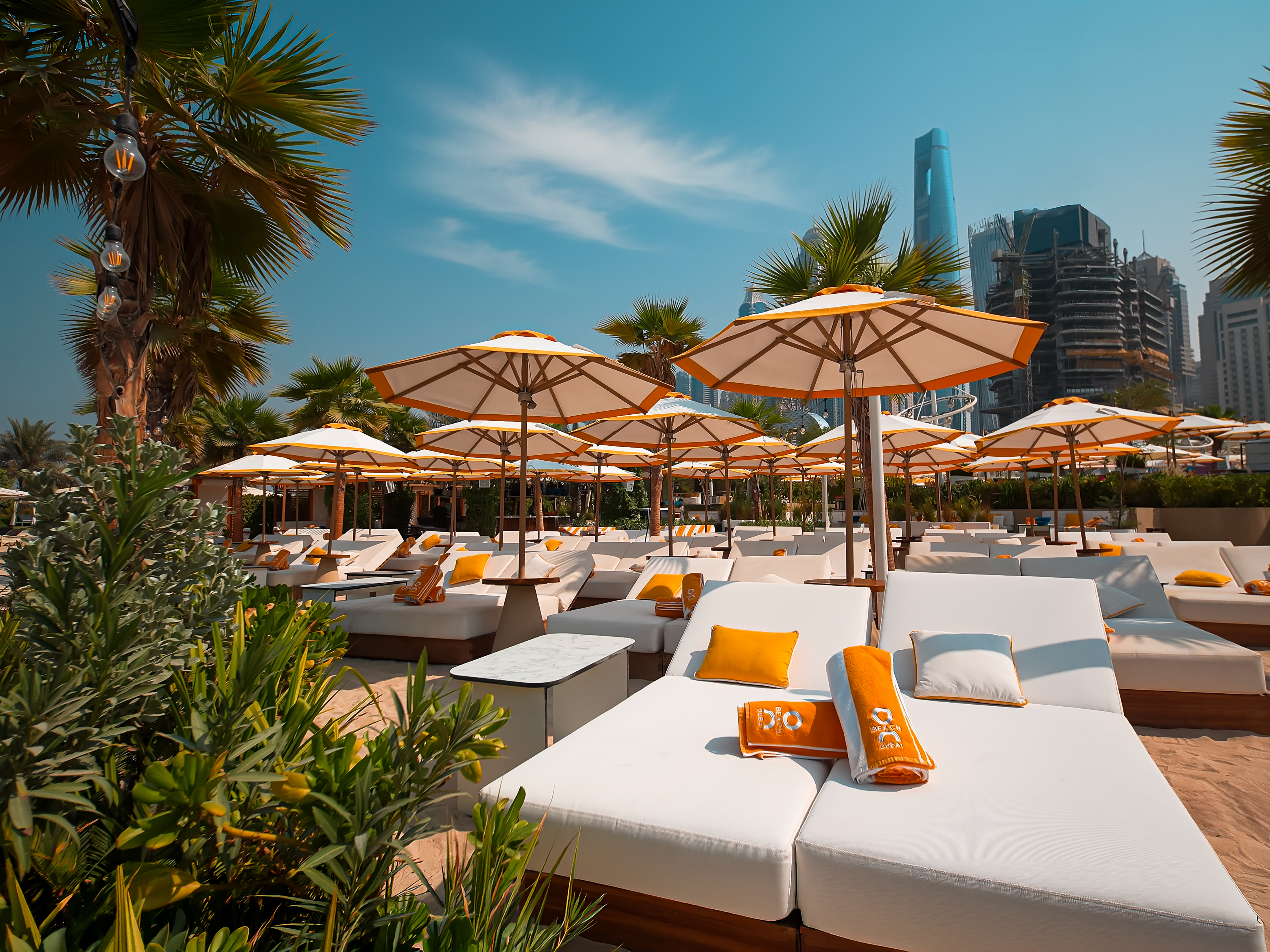 Sunlit daybeds and striped umbrellas at O Beach Dubai.