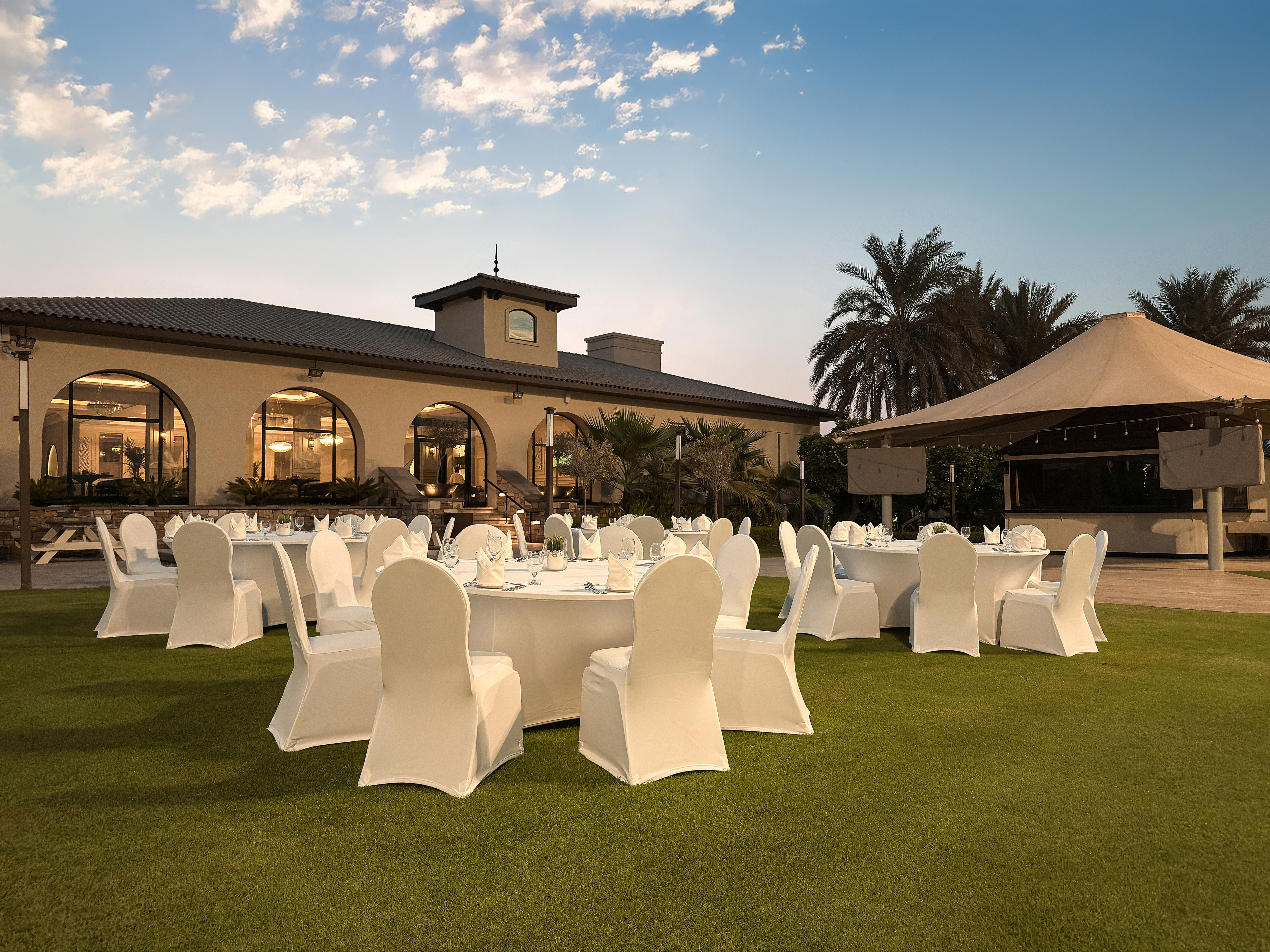 Outdoor event setup on the lawn at Saadiyat Beach Golf Club during sunset.